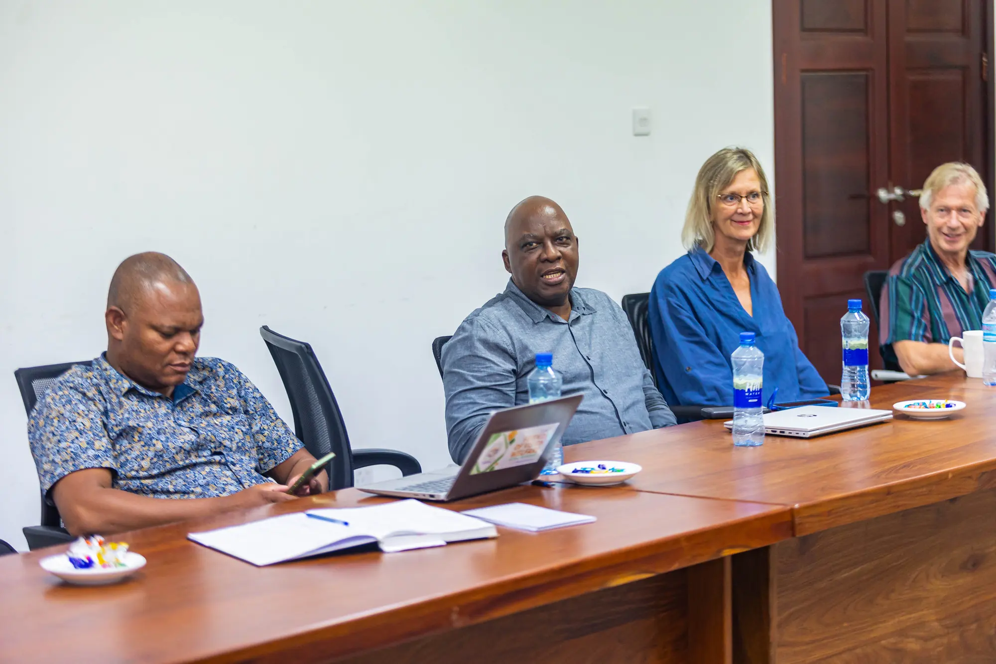 Four delegates seated along the conference table, listening to a presentation