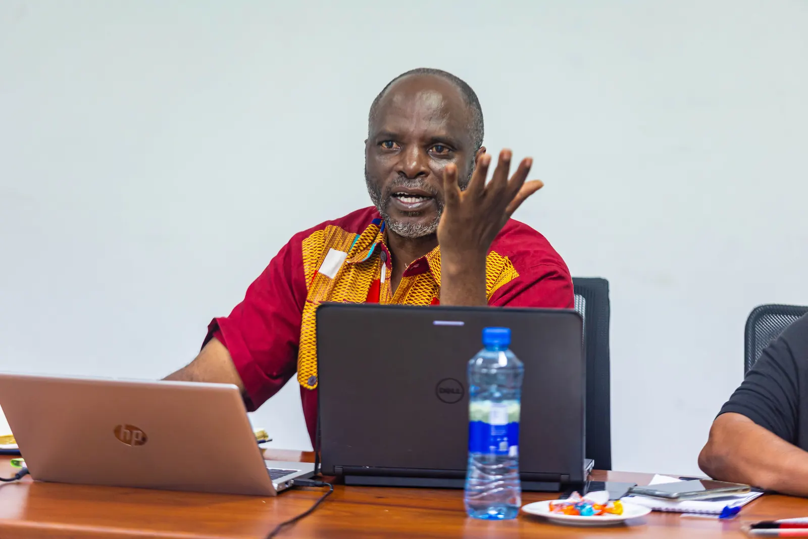 A delegate in a red-and-gold shirt making a point during the discussion